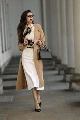 a lady in a white top, a white skirt and a trench coat